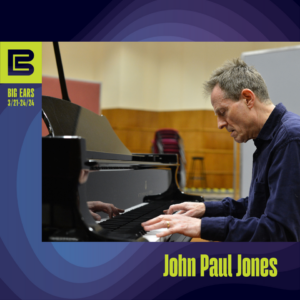 John Paul Jones playing a grand piano in an orchestra rehearsal room